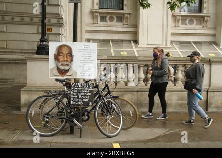 Die Demonstranten gehen an einem Schild eines Windrush-Opfers vorbei, das während der Demonstration auf einem Fahrrad auf Whitehall platziert wurde.Hunderte von Demonstranten versammelten sich auf dem Parliament Square zu einer friedlichen Demonstration von Black Lives Matter, um dem Amerikaner George Floyd Respekt zu erweisen. Die Mehrheit der Demonstranten hatte dort PPE an und die Organisatoren verteilten an alle, die Maske und Handschuhe brauchten. Stockfoto