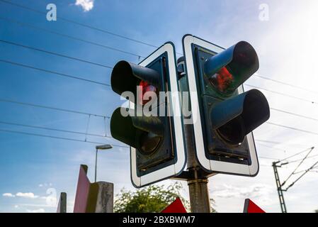 Ampel vor dem Bahnübergang mit einer roten Ampel vor nahenden Zügen warnen. Stockfoto