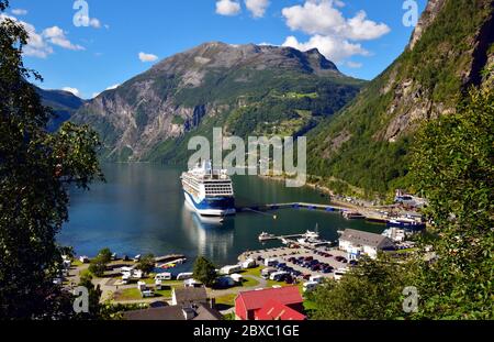 Der Kreuzfahrtterminal in Geiranger, Norwegen, mit TUI Kreuzfahrtschiff Marella Discovery an der Seite. Stockfoto