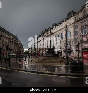 Ein einsame Tourist spaziert während der Sperre durch den Piccadilly Circus in London, während die Coronavirus-Pandemie die Welt fegt. Stockfoto