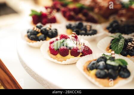 Köstliche Mini-Kuchen in Büfetts. Himbeere, Heidelbeere dekorierte Cupcakes. Verschiedene Desserts auf Party. Feier, Party, Geburtstag oder Hochzeit Stockfoto