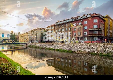 Skulpturen (entworfen von Enes Sivac 1993) hängen über dem Fluss Miljacka, in der Dämmerung.Sarajevo Innenstadt, Bosnien und Herzegowina. Stockfoto