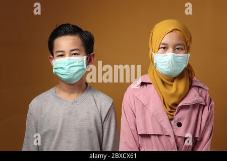 Junge und Mädchen, muslimische Bruder und Schwester tragen medizinische Maske, um covid Coronavirus-Infektion zu verhindern, soziale Distanzierung der neuen Normalität Stockfoto