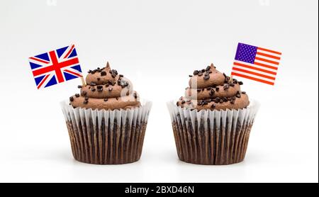 Zwei Schokoladen-Schoko-Cupcakes mit Zahnstocher-Flaggen aus den USA und Großbritannien auf Weiß isoliert Stockfoto