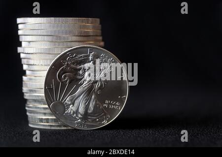 Eine glänzende neue amerikanische Silberadlermünze vor einem Stapel ähnlicher Silberadlermünzen Stockfoto