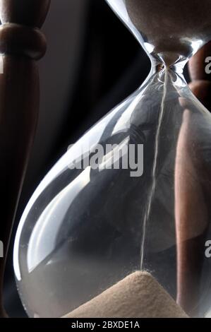 Nahaufnahme von schrägem Blick auf Sand, der durch eine Sanduhr geht, mit natürlichem Licht Stockfoto