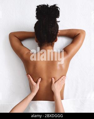 Nicht erkennbare afrikanische Frau mit Rückenmassage, weißer Hintergrund Stockfoto