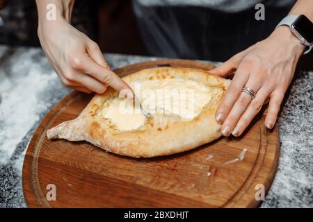Koch kocht khachapuri mit Käse und Ei. Georgische nationale Küche Stockfoto
