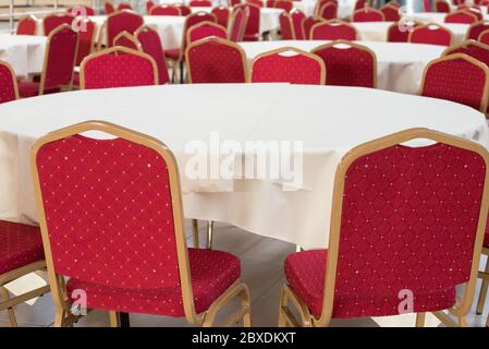 Rote Stühle mit hoher Rückenlehne und Tische mit weißen Tischdecken in einem Café Stockfoto