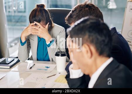 Junge Unternehmerin bei einem Geschäftstreffen verzweifelt über Firmenbankrott oder Finanzkrise Stockfoto