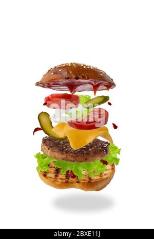 Köstlicher Burger mit fliegenden Zutaten isoliert auf weißem Hintergrund. Konzept der Levitation von Lebensmitteln. Stockfoto