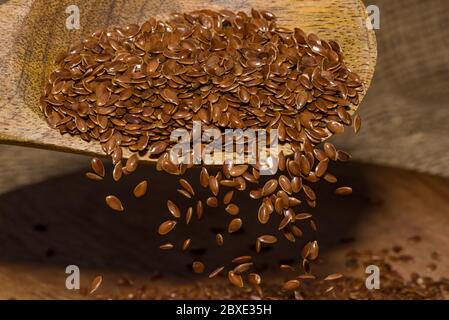 Leinsamen, die in Zeitlupe rotieren, enden. Leinsamen in einem Holzlöffel. Stockfoto
