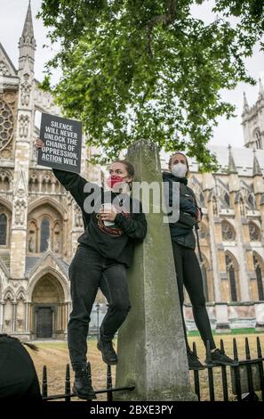 London, Großbritannien. Juni 2020. Eine weiße Frau steht auf dem Geländer der Westminster Abbey und hält ein Plakat, das während der Demonstration zu Aktionen gegen Rassismus und Ungerechtigkeit aufruft. Tausende von Menschen versammelten sich vor dem Parliament Square in London, um gegen die Ermordung von George Floyd zu protestieren und Rassengerechtigkeit zu fordern. Quelle: SOPA Images Limited/Alamy Live News Stockfoto