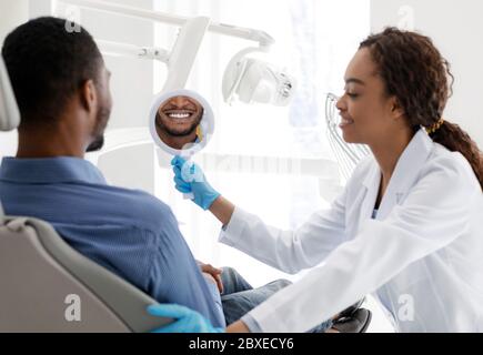 Zahnarzt halten Spiegel für den Patienten zu Zahnweiß-Behandlung Ergebnis zu überprüfen Stockfoto