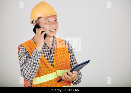 Lächelnder Auftragnehmer mit digitalem Tablet, der mit dem Kunden telefoniert Stockfoto