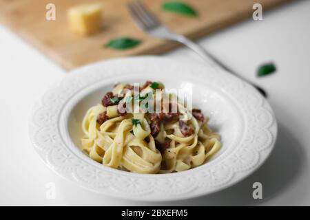 Traditionelle italienische Pasta Fettuccine Alfredo mit sonnengetrockneten Tomaten und Basilikum vegan. Sauce aus Bechamel, Milch auf pflanzlicher Basis, Olivenöl Stockfoto
