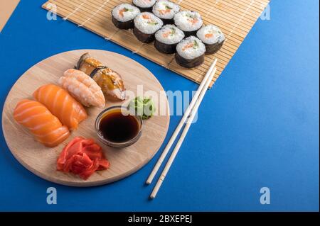 Sushi-Set Sashimi mit Lachs, Garnelen, Aal und Sushi-Brötchen auf Bambusmatte und Holzbrett serviert. Japanische Speisekarte Stockfoto