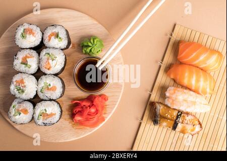 Sushi-Set Sashimi mit Lachs, Garnelen, Aal und Sushi-Brötchen auf Bambusmatte und Holzbrett serviert Stockfoto