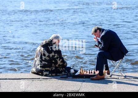 Russland, Sankt Petersburg, 23. Mai 2020: Zwei Männer spielen Schach auf dem Damm Stockfoto