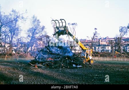 Die Nachwirkungen des "Großen Sturms" in Brighton, East Sussex, England, Großbritannien – es geschah in der Nacht des 15/16. Oktober 1987. Hier findet die große Aufreinigung auf 'The Level' statt, einem Stadtpark im Zentrum von Brighton. Ein JCB stapelt Holz und Schutt an einem großen Lagerfeuer auf 'The Level', einem Stadtpark im Zentrum von Brighton. Der große Sturm von 1987 war ein heftiger tropischer Wirbelsturm, bei dem Wirbelstürme in Großbritannien und Frankreich Opfer und große Schäden verursachten. Stockfoto