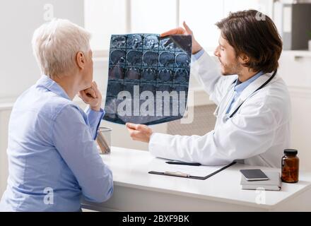 Arzt untersucht Kopf-Röntgenaufnahmen von älteren weiblichen Patienten Stockfoto