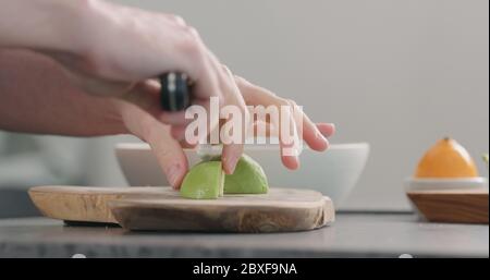 Mann schneiden reife Avocado auf Küche Arbeitsplatte Seitenansicht Stockfoto