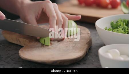 Mann schneiden reife Avocado auf Küche Arbeitsplatte Stockfoto