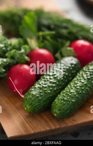 Rettich, Gurken und Grünkohl auf Olivenholzplatte Nahaufnahme Stockfoto