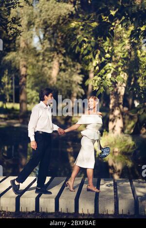 Glückliches Ehepaar, Das Gerade Verheiratet Ist Und Hände Hält, Die Im Wunderschönen Park, Vertical, Spazieren Gehen Stockfoto