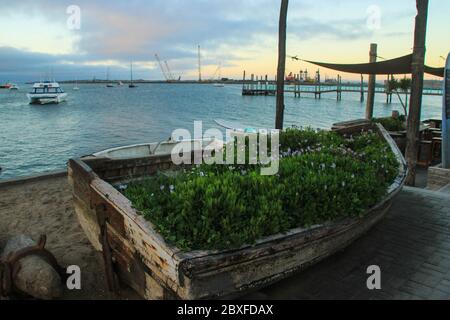 Walvis Bay, Namibia - 25. April 2015: Atlantikküste mit Steg in der Abenddämmerung. Original Blumenbeet für Blumen im Boot Stockfoto