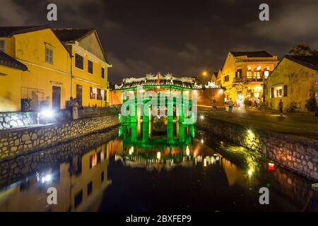 HOI AN, VIETNAM - 24. MÄRZ 2017: Die alte japanische Brücke in Hoi an bei Nacht. Reflexionen, andere Gebäude und Menschen sind zu sehen. Stockfoto