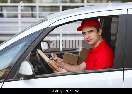 Rechtzeitige Lieferung per Auto. Courier in Auto nimmt Eintrag in Tablet Stockfoto