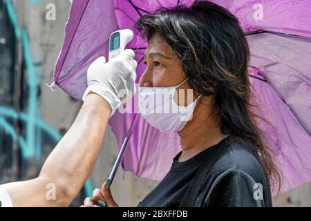 Körpertemperatur-Check und Gesichtsmaske während der Covid-Pandemie, Bangkok, Thailand Stockfoto