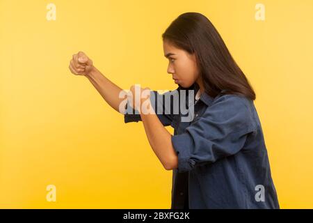 Lasst uns kämpfen! Seitenansicht von selbstbewussten mutigen Mädchen in Denim-Shirt Fäuste geballt halten, Boxen und Stanzen auf Seite, Kampf und Selbstverteidigung Konz Stockfoto