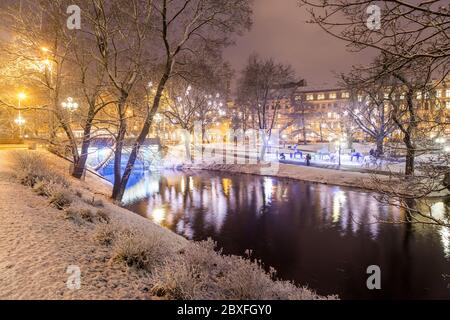 RIGA, LETTLAND - 2. JAN 2017: Blick auf den Bastejkalna Park in Riga im Winter bei Nacht. Schnee und Menschen sind zu sehen. Stockfoto