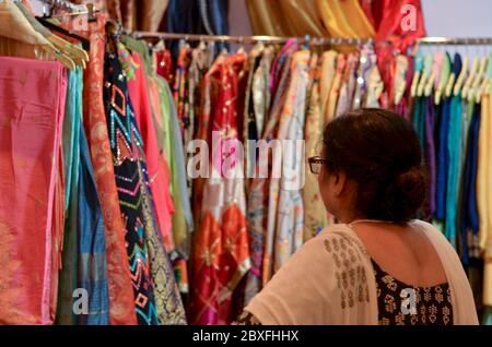 Eine ältere indische Frau trägt eine Brille, die Designerin Kurta ( Salwar Kamiz) überprüft und in einem Geschäft in Dilli Haat oder Sarojini nagar Markt in Neu Delhi ausgestellt wird Stockfoto