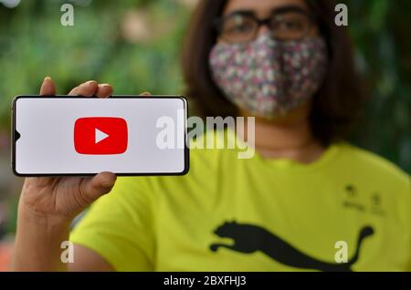 Delhi, Indien, 2020. Mädchen trägt Maske zeigen Youtube-App auf Handy unter häuslicher Quarantäne für Corona-Virus (Covid-19) Krankheit Pandemie. YouTube ist sehr po Stockfoto