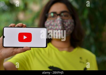 Delhi, Indien, 2020. Mädchen trägt Maske zeigen Youtube-App auf Handy unter häuslicher Quarantäne für Corona-Virus (Covid-19) Krankheit Pandemie. YouTube ist sehr po Stockfoto