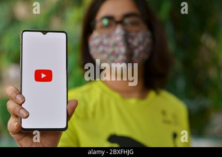 Delhi, Indien, 2020. Mädchen trägt Maske zeigen Youtube-App auf Handy unter häuslicher Quarantäne für Corona-Virus (Covid-19) Krankheit Pandemie. YouTube ist sehr po Stockfoto