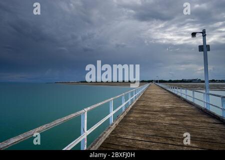 Leerer Pier mit Sturmwolken im Hintergrund, Urangan Pier, Hervey Bay Queensland, Australien Stockfoto