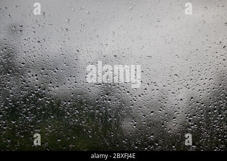 Regentropfen am Fenster - Blick aus dem Fenster nach außen, regnerisches Wetter, Textur Hintergrund Stockfoto