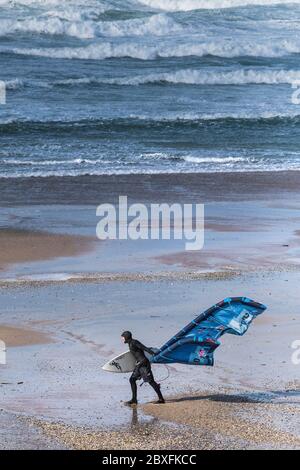 Ein Kite-Boarder, der seine Ausrüstung zum Kite-Boarding im Surfing bei starkem Wind am Fistral Beach in Newquay in Cornwall trägt. Stockfoto