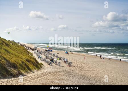 Blick auf Sylter Strand mit Dünen, Liegen und der Nordsee. Typische Strandlandschaft mit Urlaubern im Sommer auf der deutschen Wattenmeerinsel. Stockfoto