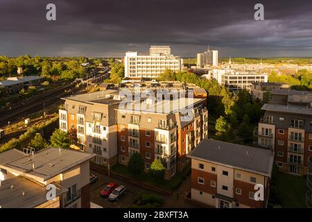 Eine Luftaufnahme von einem stürmischen Himmel mit Regenwolken während des Sonnenuntergangs mit dramatischer Beleuchtung über Basingstoke Stadtzentrum mit Wohnungen und Büros, Großbritannien Stockfoto