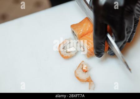 Der japanische Koch bereitet Sushi auf einem weißen Brett zu Stockfoto