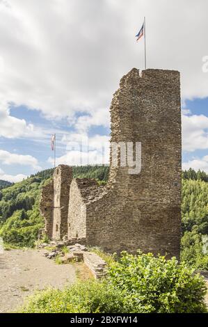 Die Ruine des Turms einer mittelalterlichen Burg, von der Sonne an einem leicht bewölkten Sommertag beleuchtet. Markierungen oben. Stockfoto