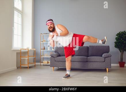 Lustiger fetter Mann in roten Shorts und weißem T-Shirt lächelnd Übungen im Raum machen Stockfoto