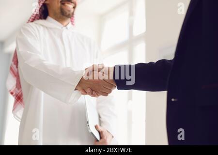 Handschlag arabischer und europäischer Geschäftsleute im Büro. Stockfoto