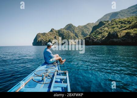 Rückansicht des Mannes, der die Natur auf dem Boot genießt und die tropische Insel betrachtet. Reise durch Asien: El Nido, Palawan, Philippinen Stockfoto