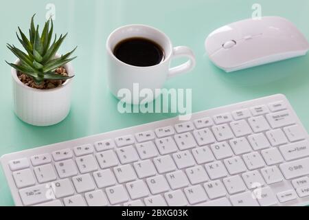Büroarbeitsplatz, Computertastatur mit Kaffeetasse, gleichmäßig angeordnete Gegenstände, helle Farben, Stockfoto